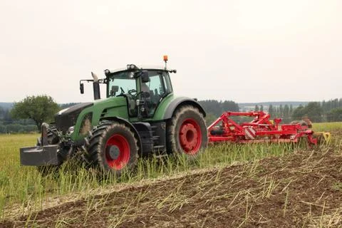 Tractor with attached tilling tool preparing field with rape stubble for fe.. Stock Photos
