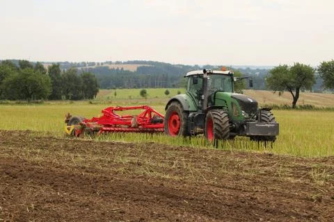 Tractor with attached tilling tool preparing field with rape stubble for fe.. Stock Photos