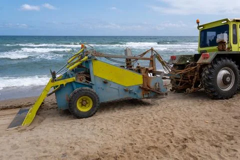 Tractor with beach cleaning machine removing debris from sandy shore Stock Photos