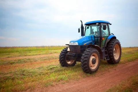 Tractor of blue color standing in summer in grass field Foto stock