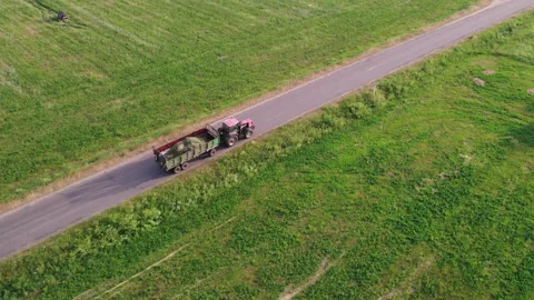 Tractor carries a trailer with hay through the countryside 動画素材 158106893