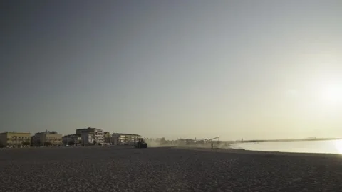 Tractor Cleaning Sandy Beach at Sunrise with Golden Sun flare France Stock Footage 342438300