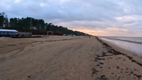 A tractor cleans and levels an empty beach near a seasonal waterfront cafe Stock Footage 323920993