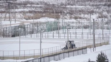Tractor cleans snow on a court for skating Stock Footage