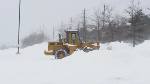 Tractor clears a parking lot during a heavy snow storm Stock Footage 264628259