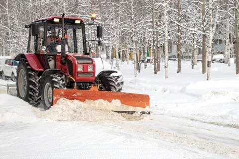 A tractor clears the road from snow. Stock Photos