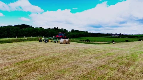 Tractor Collects Round Bales During Hay Harvest on Open Farming Field Vídeo Stock 331222445