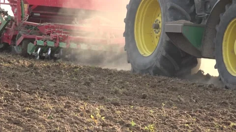 Tractor cultivating and sowing wheat in spring against sunlight. Closeup. 4K Stock Footage 59643343