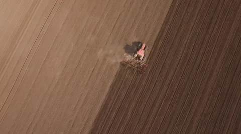 Tractor cultivating arable land for seeding crops, aerial view Stock Footage 62465403