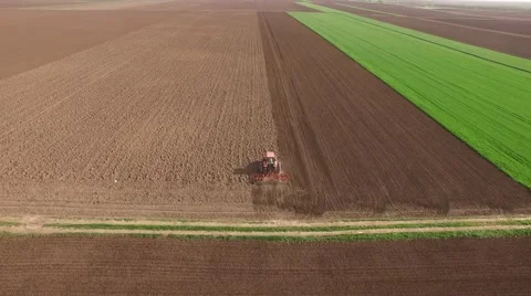 Tractor cultivating arable land for seeding crops, aerial view Stock Footage 62467381