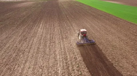Tractor cultivating arable land for seeding crops, aerial view Stock Footage 62470171