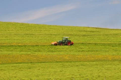 Tractor cutting meadow Stock Photos
