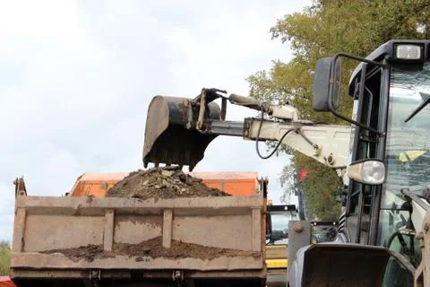 The tractor deepens a section of the road with a bucket to apply a patch of a Photos
