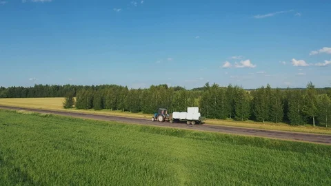 Tractor Drive With Trailer For Cut Grass In Rolls And Wrapped In White Package Stock Footage 123597656