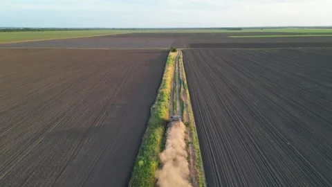A tractor drives down a dirt road through a field at sunset Stock Footage 282209834