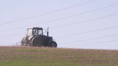 Tractor drives through the field against the background of the pipes of the Stock Footage 142671871