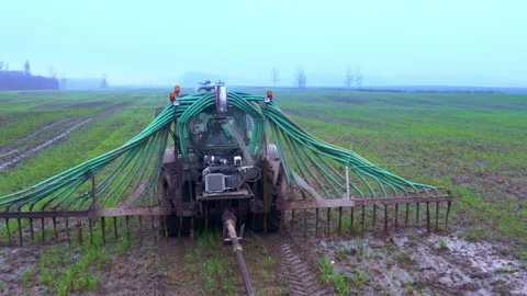 The tractor drives through the field and released agricultural fertilizer Autumn Stock Footage 219729802