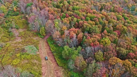 A Tractor driving in forest aerial top view. Fall colors countryside woodland 動画素材 322145205