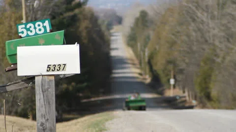 Tractor driving up steep hill on old country road by two mailboxes. 1080p 24. Stock Footage 22772148
