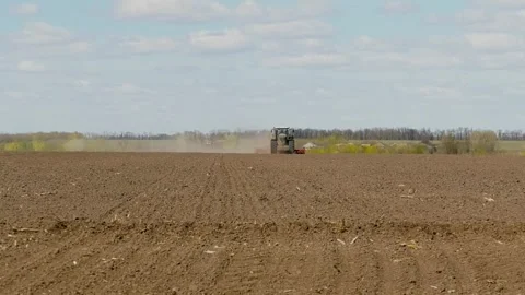 Tractor driving through a field with a harrow and seeder Stock Footage 348268276