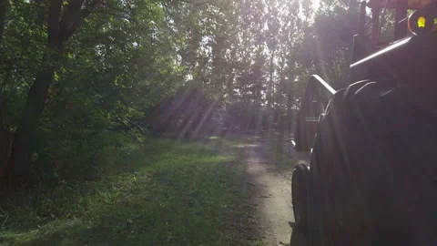 Tractor driving through forest path on sunny day - close up - side profile 스톡 동영상 132572345