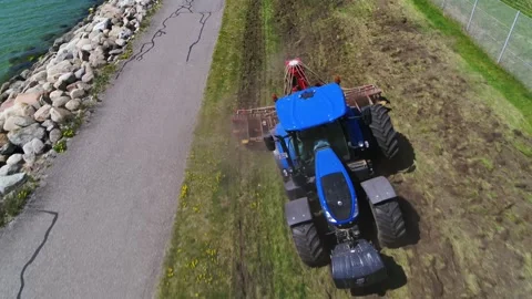 Tractor driving towards camera while cutting grass in a public area Stock Footage 298653559