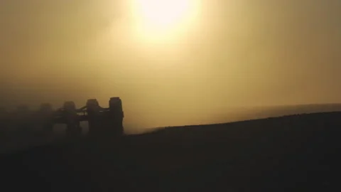 Tractor in the dust working in the field at sunset. Vidéo 132104906