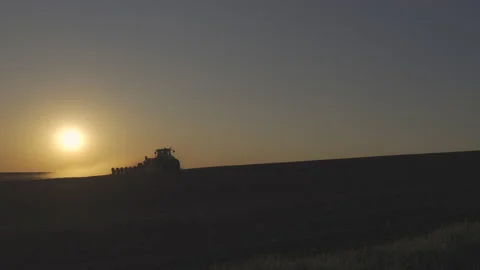 Tractor in the dust working in the field at sunset.  Vidéo 132105019