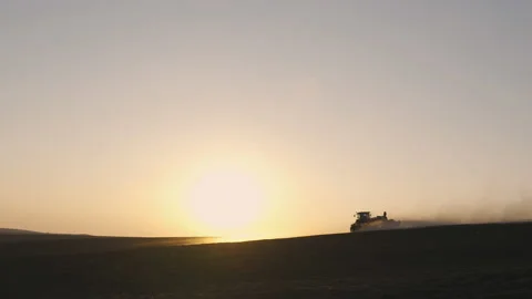 Tractor in the dust working in the field at sunset. Vidéo 132105292