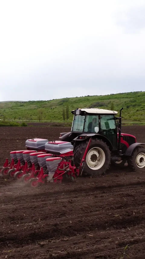 Tractor equipped with a seed drill is actively planting seeds in a freshly Stock Footage 325202514