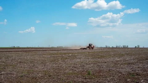 A tractor in a field on blue sky background with clouds. Stock Footage 129624748