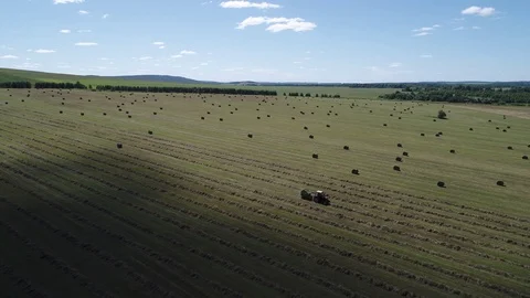 Tractor in field with haystacks 16-9 Stock Footage 102285959