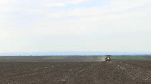 The tractor in the field preparing the ground for sowing Stockbeeldmateriaal 104693476