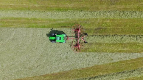 Tractor in field preparing hay bales for collection in English countryside Stock Footage 293590504