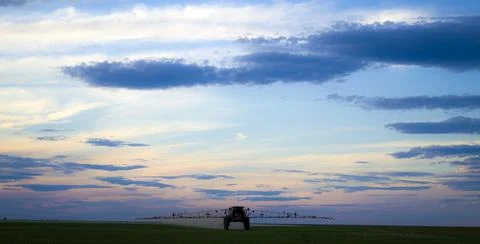 A tractor in the field sprays fields at sunset, a difficult day for the hard Stock Photos