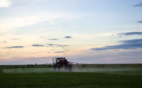 A tractor in the field sprays fields at sunset, a difficult day for the hard Stock Photos