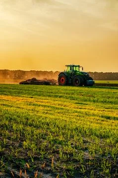 Tractor in the field under sunset light, tillage in spring. selective focus Stock Photos