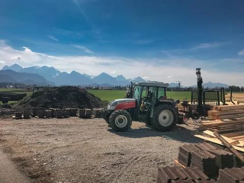 A tractor in front of big mountains in the background. Stock Photos