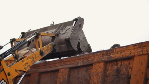 Tractor with front bucket unloading soil into truck Stock Footage 323870635
