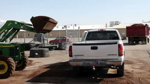 A tractor with front end loader loading fertilizer into a pickup truck HDP Stock-Footage 3165655
