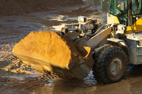 Tractor front wheel loader with sand in bucket. Earthmoving works at Stock Photos
