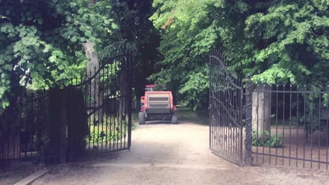 Tractor goes through an iron gate in a park Видео 134818865