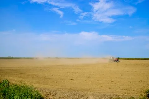 Tractor with a grader aligns the soil on the field. The tractor raised dust. Foto stock