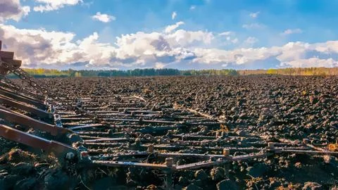 Tractor harrow on a background of fresh arable land and clouds. Watercolor il Illustrazione stock