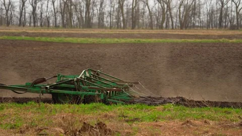 Tractor with harrow system plowing ground on cultivated farm field, pillar of Stock Footage 191430017