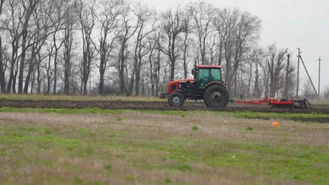 Tractor with harrow system plowing ground on cultivated farm field, pillar of Stock Footage 201097697