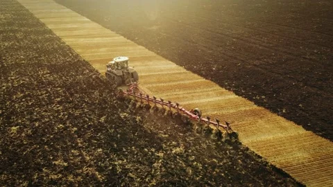 Tractor with harrow system plowing ground on cultivated farm field Vidéo 204748083