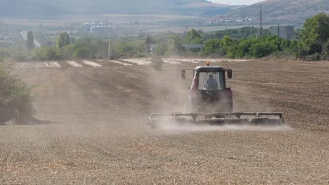 Tractor harrowing a dry field creating dust clouds Stock Footage 345927112
