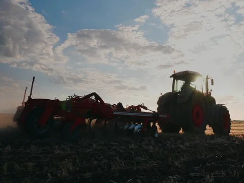 Tractor harrows the field at sunset. Steadicam shot Stock Footage 76846343