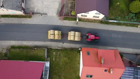 Tractor Hauling Two Trailers Loaded With Round Bales of Hay Through Quaint Stock Footage 303378665